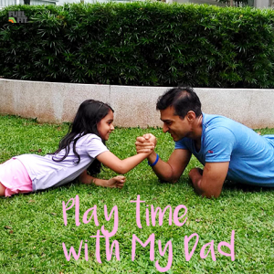 Child and Dad arm wrestle for fun on grass